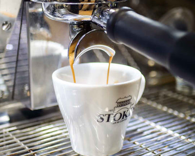Coffee pouring into espresso cup from a machine.