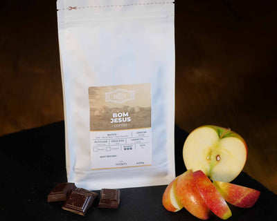 White Coffee Bag with apple and chocolate next to it to show the tasting notes.