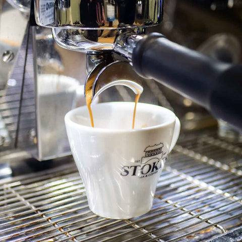 Coffee pouring into espresso cup from a machine.