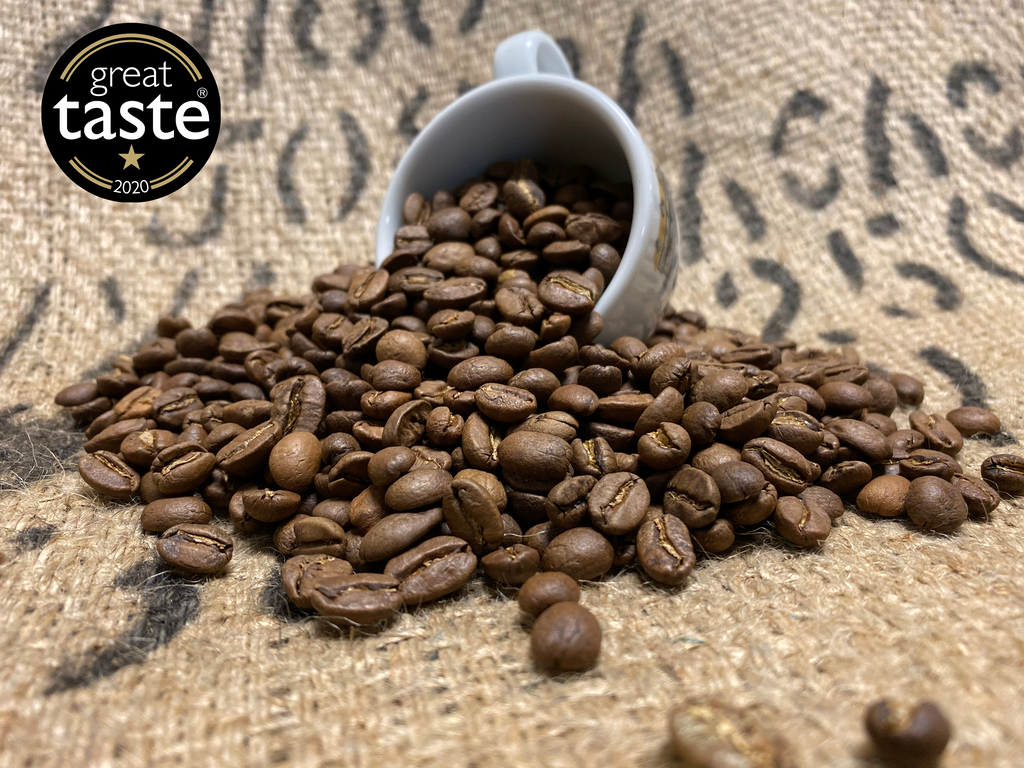 Blue Mountain Blend Coffee Beans coming out of espresso cup. Great taste badge in the corner. 