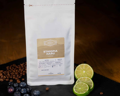 White Bag of speciality coffee beans with blueberry and lime to show tasting notes.